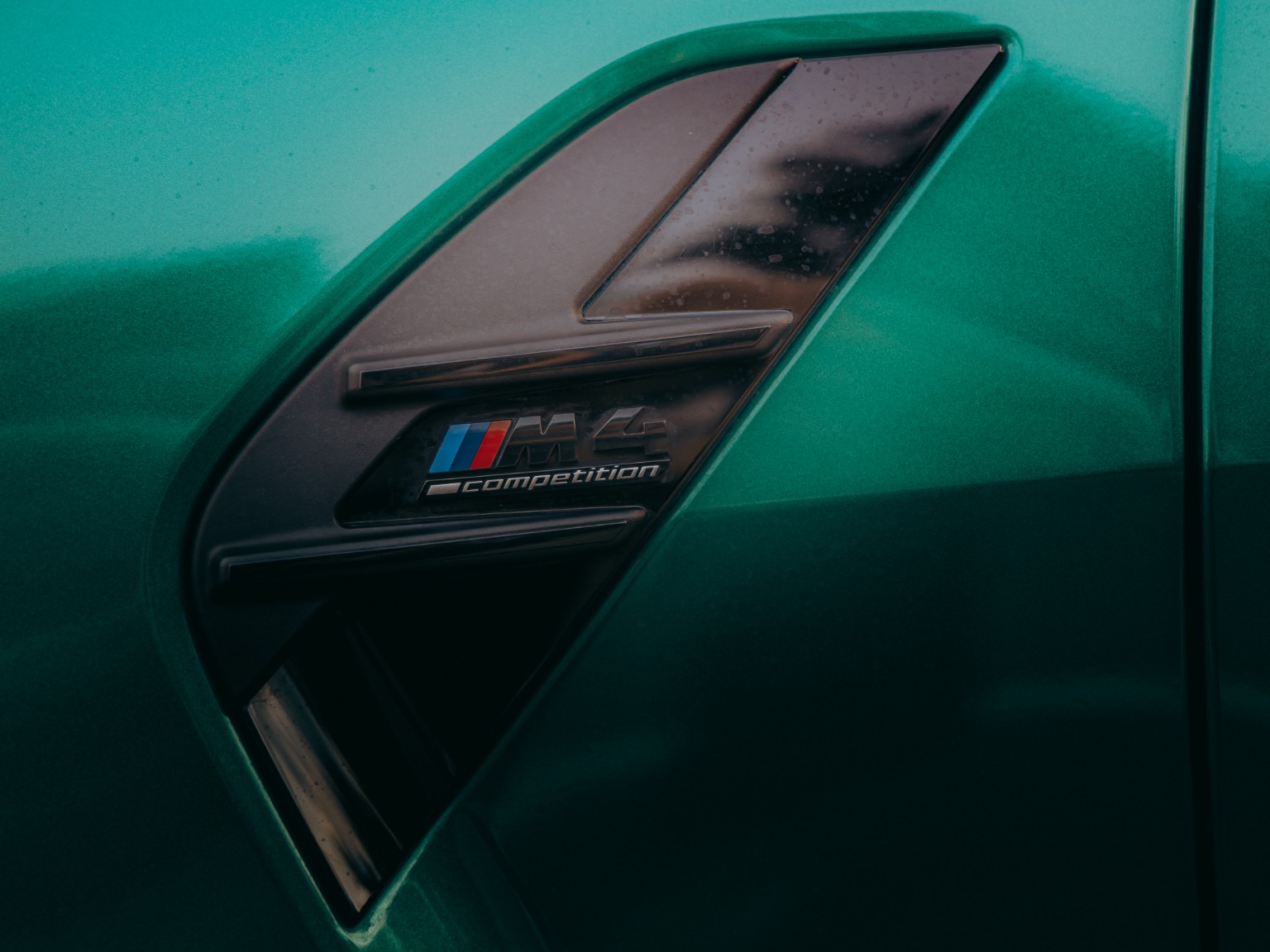 Détail du badge M4 Competition sur la carrosserie verte